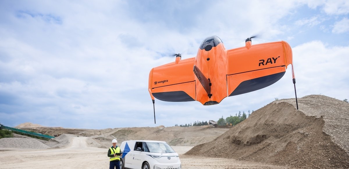 wingtraray fixed-wing VTOL drone flying over construction site.