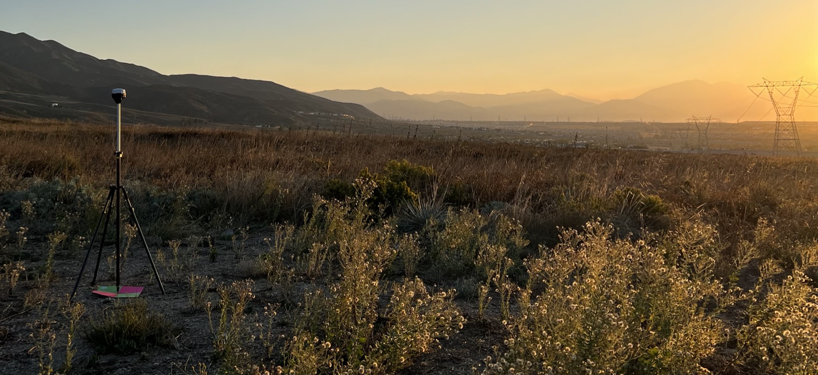 GNSS base station set up on a survey site at sunset.
